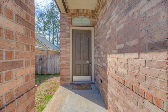 property entrance with fence and brick siding