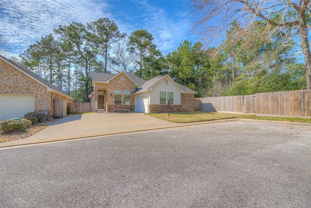 view of front of house with an attached garage, brick siding, fence, driveway, and roof with shingles