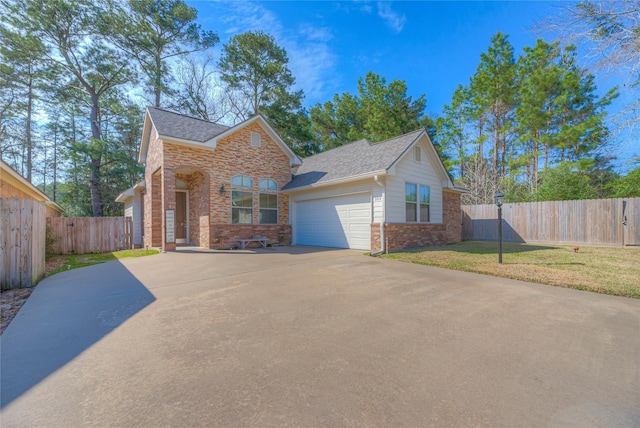 traditional-style home with driveway, an attached garage, fence, a front lawn, and brick siding