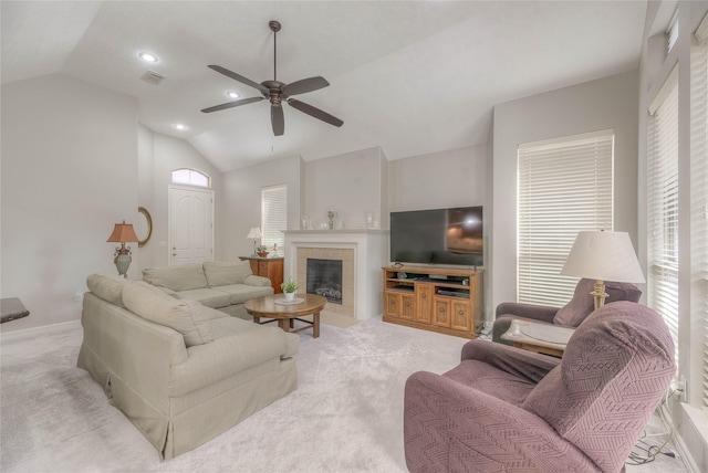 living area with ceiling fan, light colored carpet, visible vents, vaulted ceiling, and a tiled fireplace