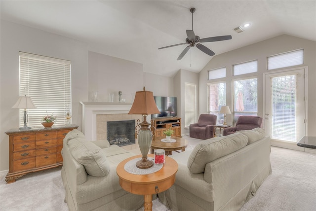 living room with a fireplace, visible vents, vaulted ceiling, and light colored carpet