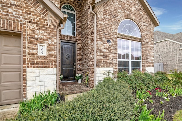 entrance to property with brick siding and an attached garage