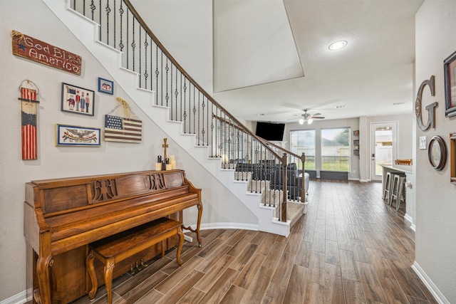 staircase featuring ceiling fan, baseboards, and wood finished floors