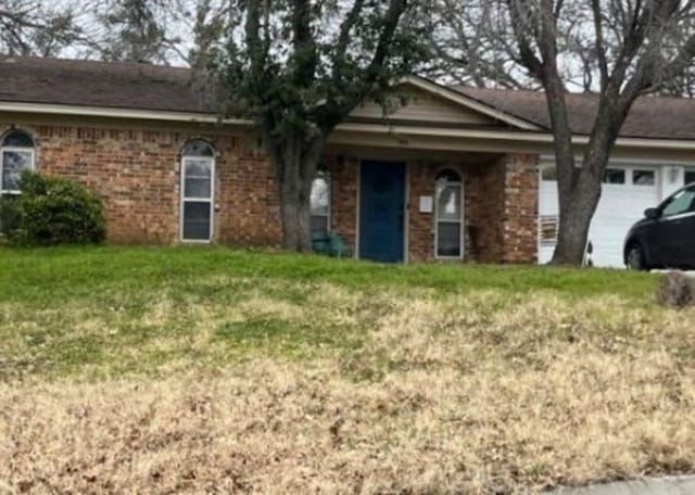 single story home featuring an attached garage, a front lawn, and brick siding