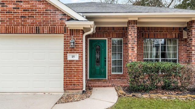 doorway to property featuring an attached garage, roof with shingles, and brick siding