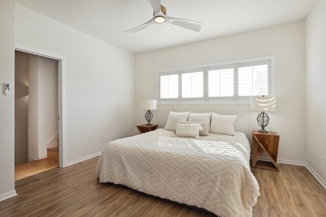 bedroom with wood finished floors, a ceiling fan, and baseboards