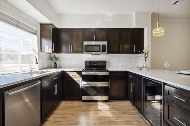 kitchen featuring beverage cooler, visible vents, decorative backsplash, appliances with stainless steel finishes, and a sink