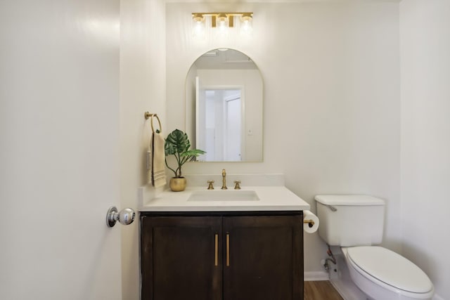 bathroom with toilet, baseboards, wood finished floors, and vanity