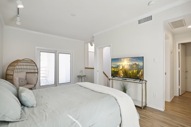 bedroom with ornamental molding, light wood-style flooring, visible vents, and baseboards