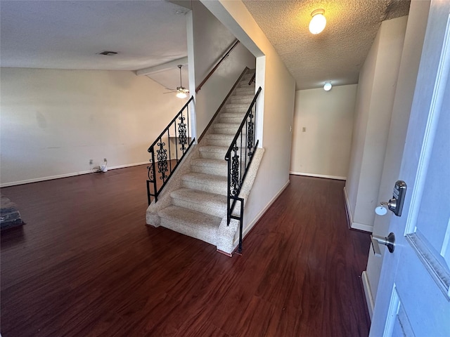 stairs with a textured ceiling, wood finished floors, a ceiling fan, baseboards, and vaulted ceiling