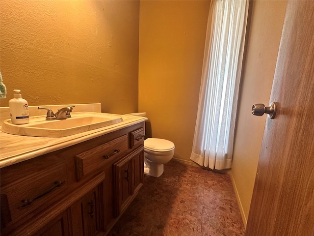 bathroom with baseboards, vanity, and toilet