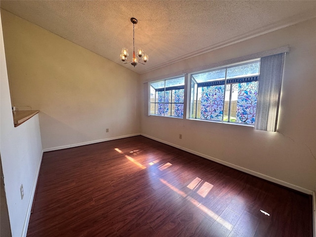 empty room featuring dark wood-style floors, a notable chandelier, lofted ceiling, a textured ceiling, and baseboards