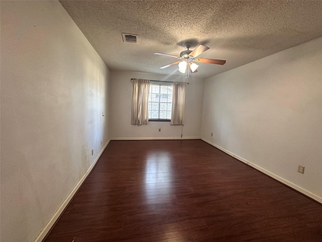 unfurnished room featuring baseboards, visible vents, dark wood-style floors, ceiling fan, and a textured ceiling