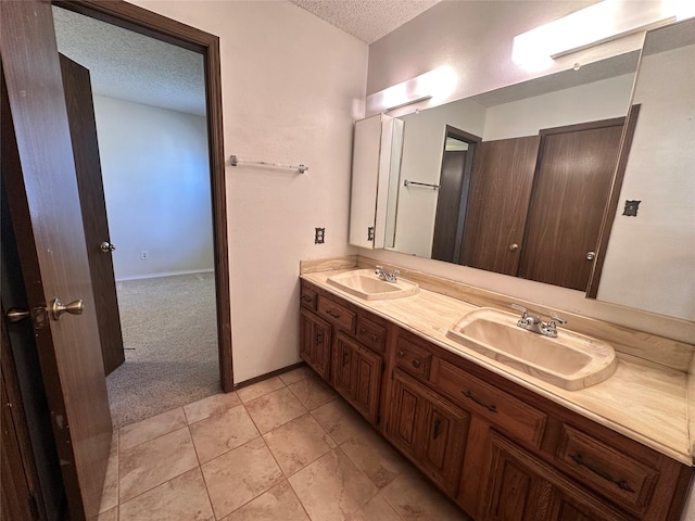 full bath featuring tile patterned flooring, a sink, a textured ceiling, and double vanity