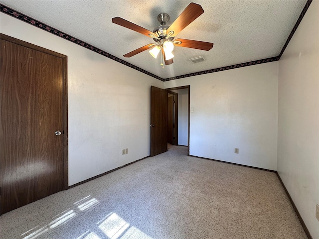 unfurnished bedroom featuring ornamental molding, visible vents, a textured ceiling, and light carpet