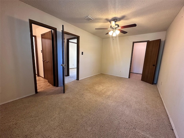 unfurnished bedroom with light carpet, baseboards, visible vents, a ceiling fan, and a textured ceiling