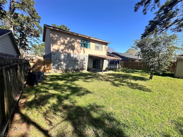 back of property with a yard, a fenced backyard, and brick siding