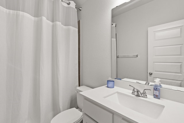 bathroom featuring a textured wall, vanity, and toilet