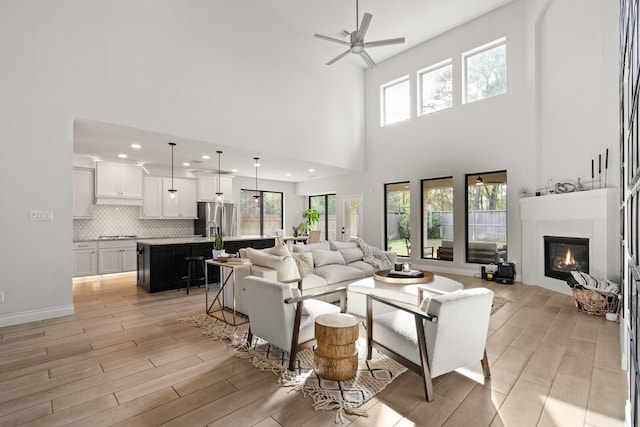 living room with light wood finished floors, plenty of natural light, ceiling fan, and a glass covered fireplace