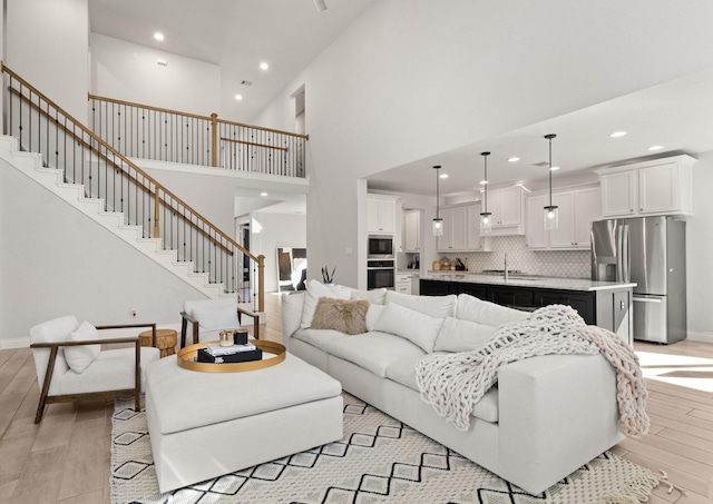 living area featuring light wood-style floors, baseboards, stairway, and recessed lighting