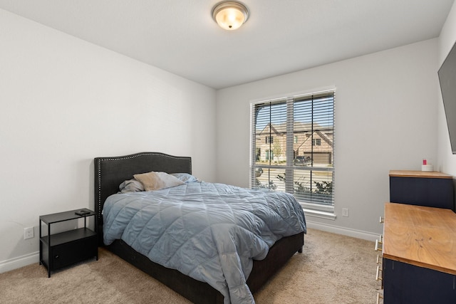 bedroom featuring light carpet and baseboards