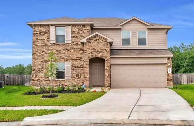 traditional-style home with driveway, brick siding, a front yard, and fence