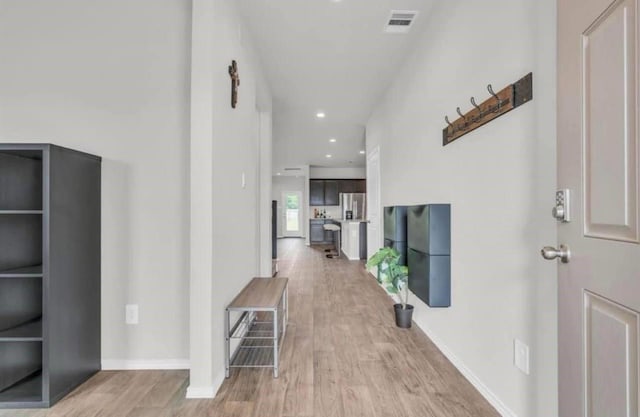 hallway with visible vents, baseboards, and light wood-style flooring