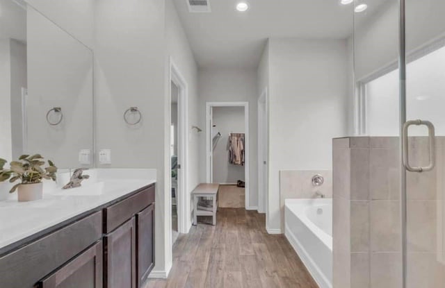 full bathroom featuring visible vents, a garden tub, wood finished floors, a shower stall, and vanity