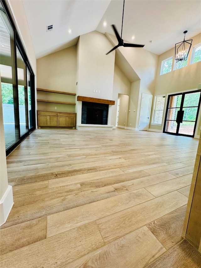 212 Rim Rock Rd, Huntsville, TX 77340 - unfurnished living room with high vaulted ceiling, light wood finished floors, a chandelier, ceiling fan, and a fireplace with raised hearth