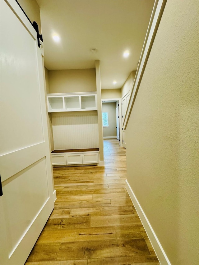 212 Rim Rock Rd, Huntsville, TX 77340 - hall featuring light wood-style floors, baseboards, a barn door, and recessed lighting