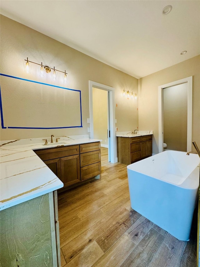 212 Rim Rock Rd, Huntsville, TX 77340 - bathroom featuring wood finished floors, two vanities, and a freestanding bath