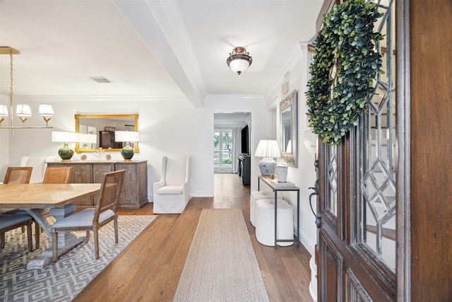 foyer entrance featuring baseboards, visible vents, ornamental molding, and wood finished floors