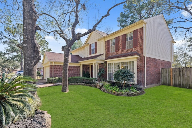 view of front of house featuring an attached garage, brick siding, a front yard, and fence