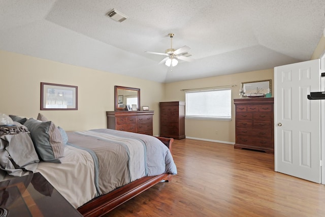 bedroom featuring baseboards, visible vents, vaulted ceiling, a textured ceiling, and light wood-style floors