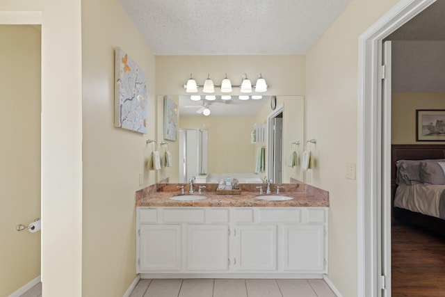 bathroom with double vanity, ensuite bath, a textured ceiling, and a sink