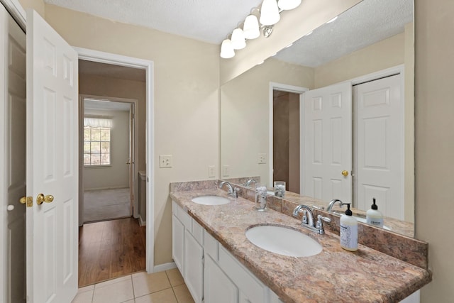 full bathroom featuring double vanity, tile patterned flooring, a sink, and baseboards