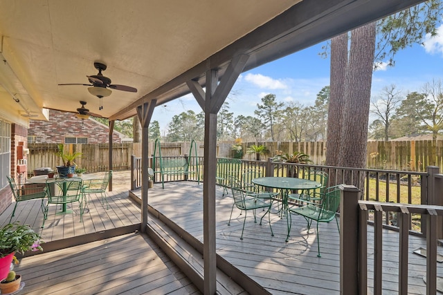 wooden terrace featuring outdoor dining space, a fenced backyard, and ceiling fan