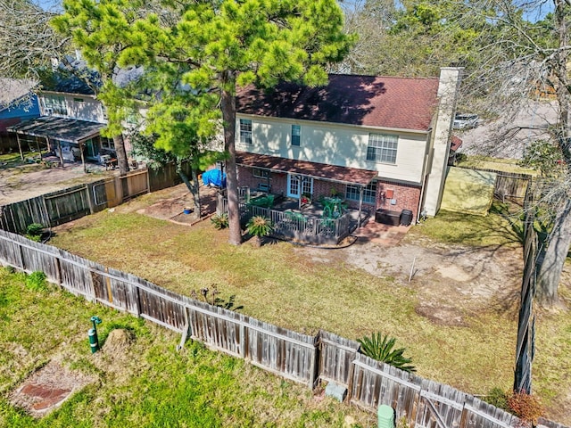 back of property with a fenced backyard, a yard, a chimney, and brick siding