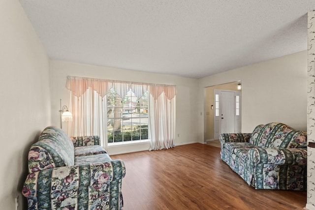 interior space featuring a textured ceiling, wood finished floors, and baseboards