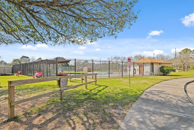 view of property's community featuring a lawn and fence