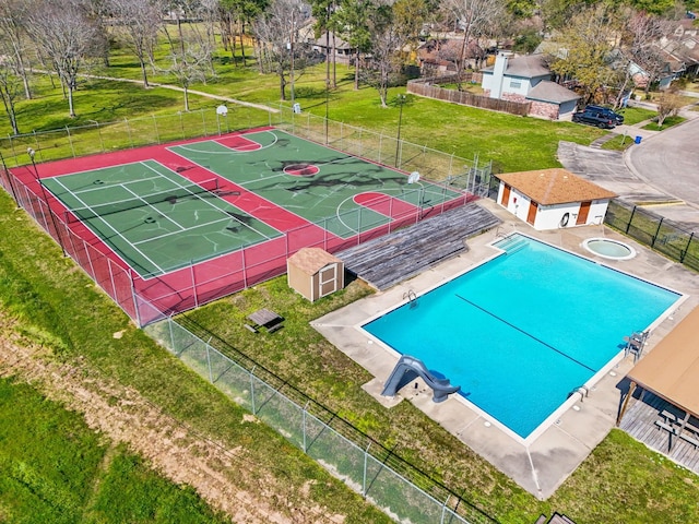 community pool featuring community basketball court, a yard, fence, and an outdoor structure