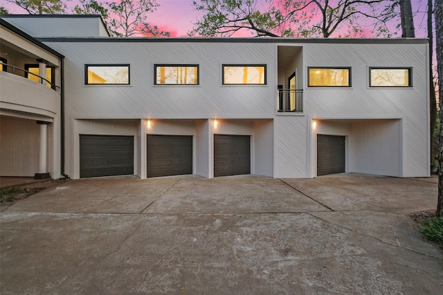 view of front of property featuring a balcony, concrete driveway, and a garage