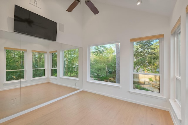 unfurnished sunroom with lofted ceiling, a ceiling fan, and visible vents