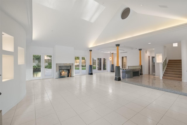 interior space featuring high vaulted ceiling, light tile patterned flooring, a fireplace, stairs, and french doors