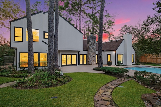 back of house featuring a patio, fence, a fenced in pool, a yard, and a chimney