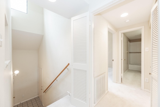 corridor with carpet floors, baseboards, visible vents, and an upstairs landing