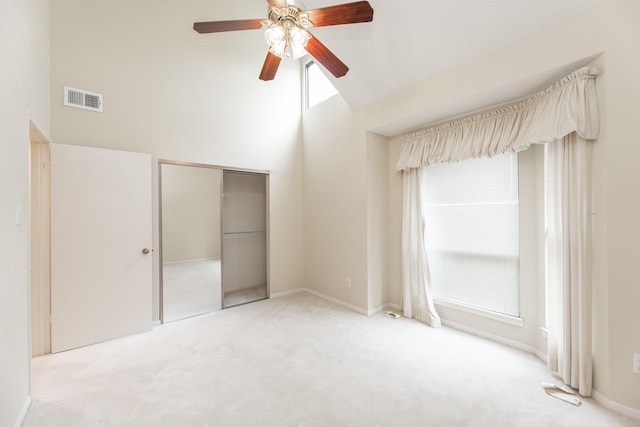 unfurnished bedroom featuring high vaulted ceiling, carpet floors, visible vents, baseboards, and a closet