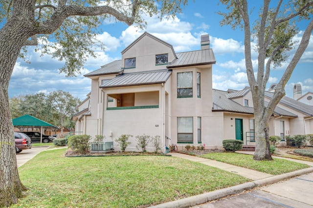 multi unit property featuring a standing seam roof, metal roof, stucco siding, a chimney, and a front yard