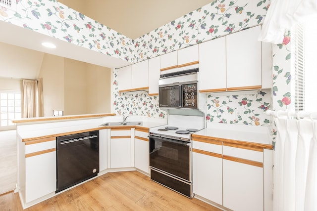 kitchen featuring a peninsula, range with electric cooktop, a sink, black dishwasher, and wallpapered walls