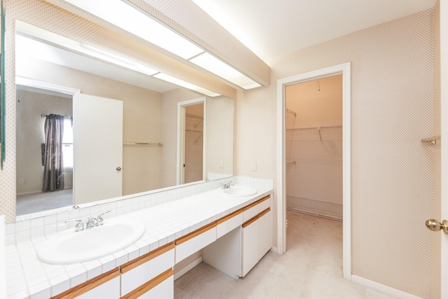 full bath with a sink, a spacious closet, and double vanity